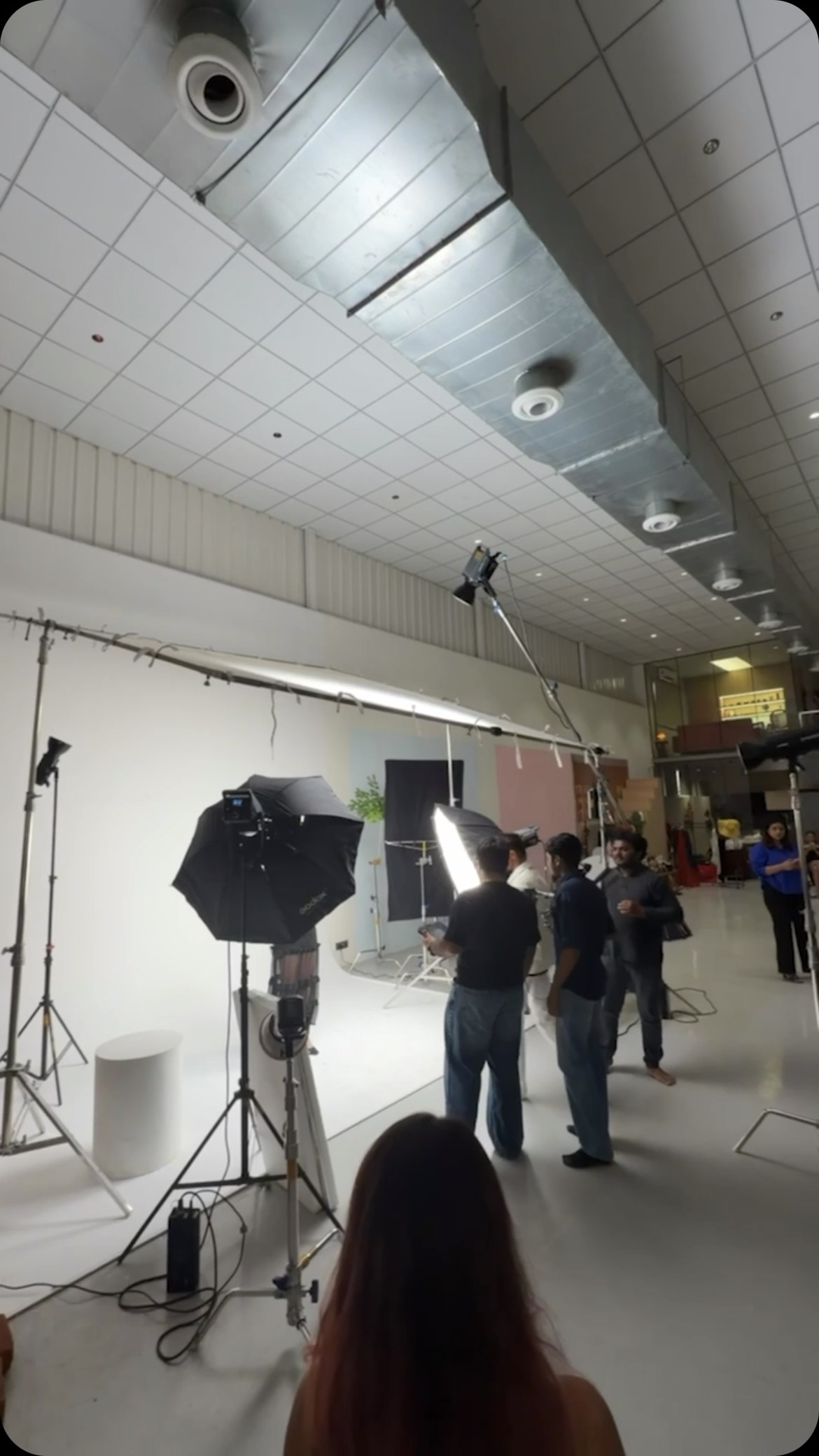 The studio floor mid-shoot, with lighting rigs, softboxes and crew around a white cyclorama